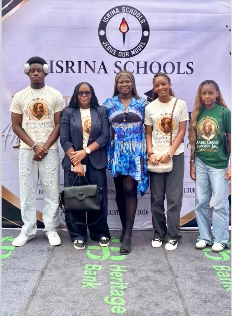 Five people standing in front of an ISRINA Schools banner