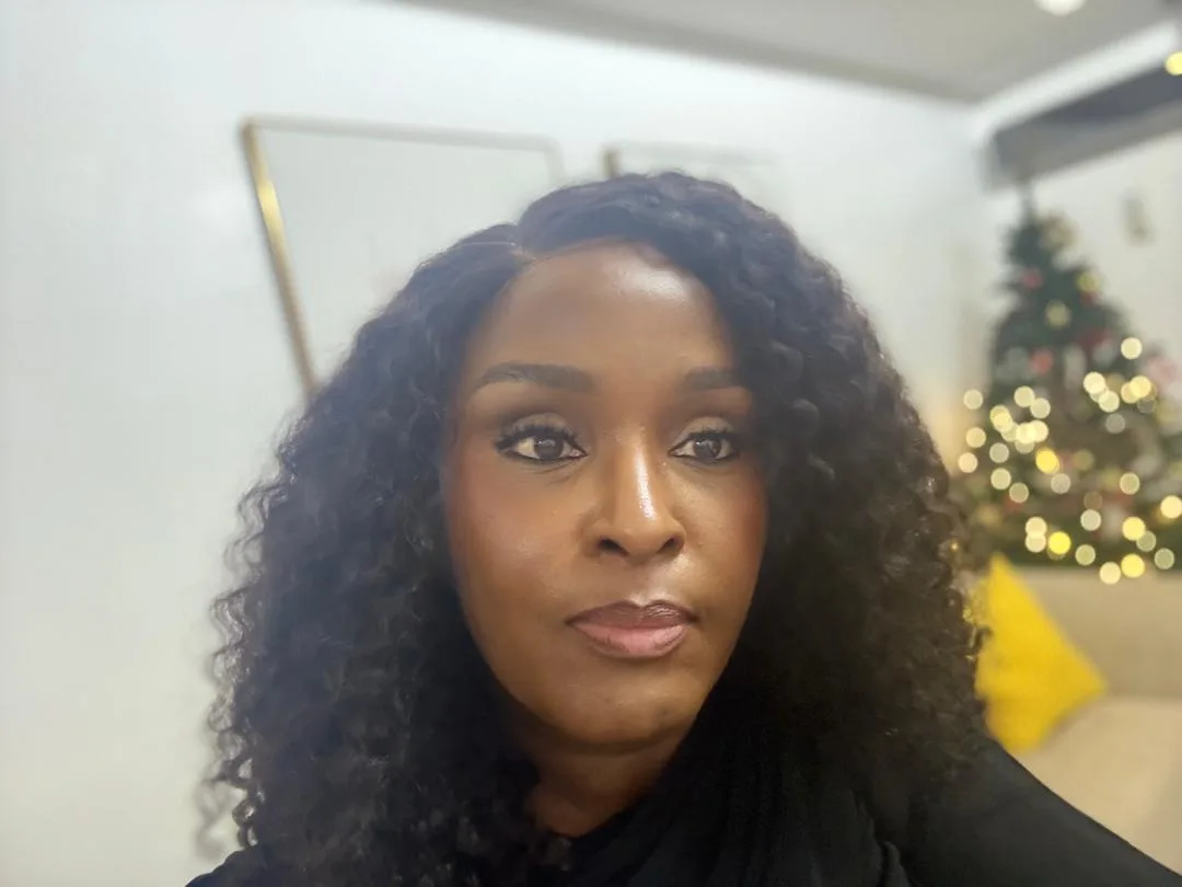 Sowari Akosionu looking at the camera indoors, with a decorated tree behind