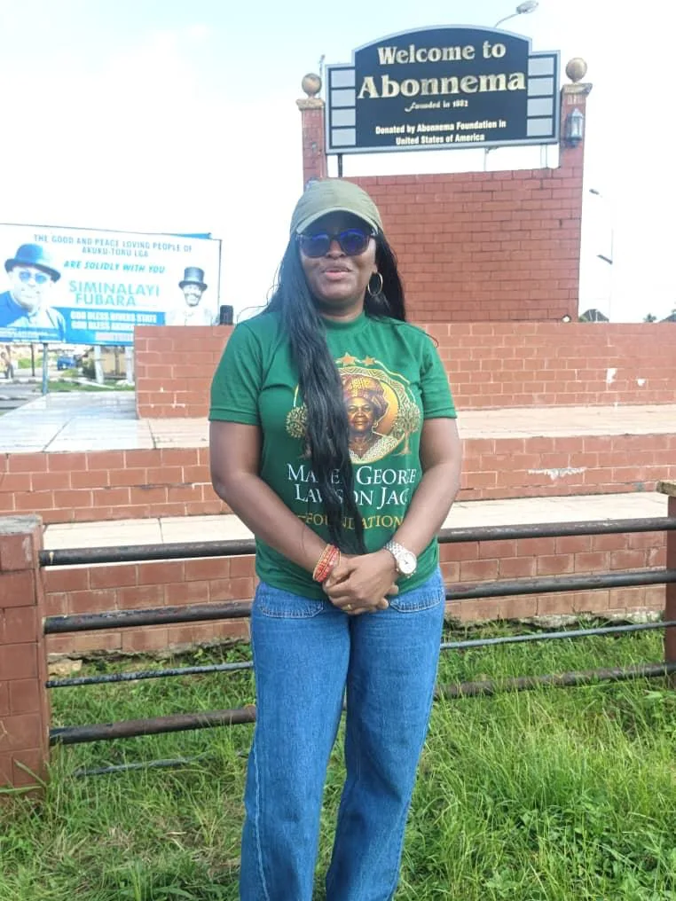 Sowari Akosionu standing on grass in front of a welcome sign at Abonema
